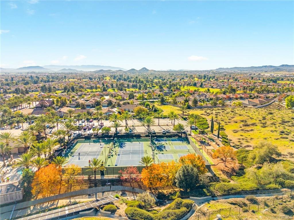 Aerial view of tennis and pickleball courts at The Oasis 55+ community in Menifee CA with surrounding neighborhood and mountain views